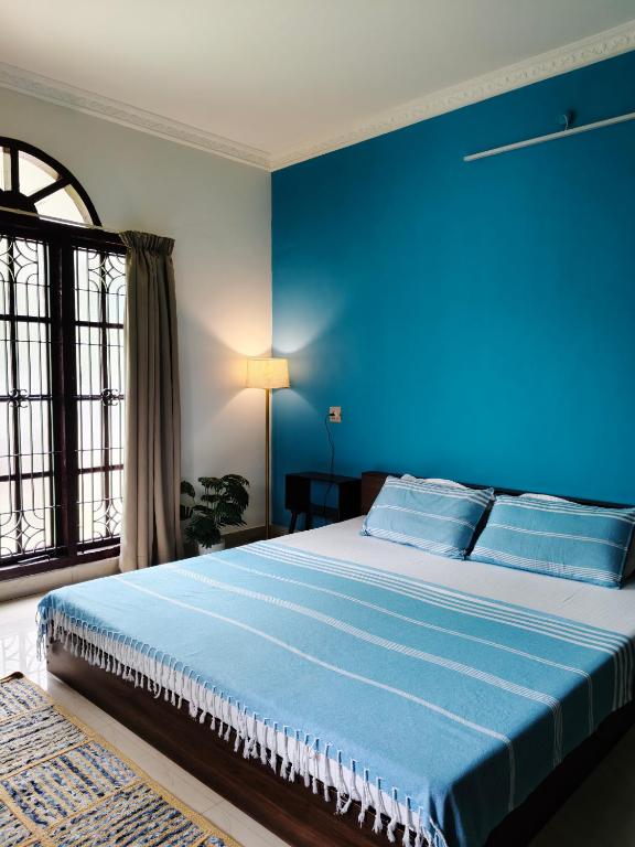 a blue bedroom with a bed with a blue wall at Aurena Stays Varkala in Varkala
