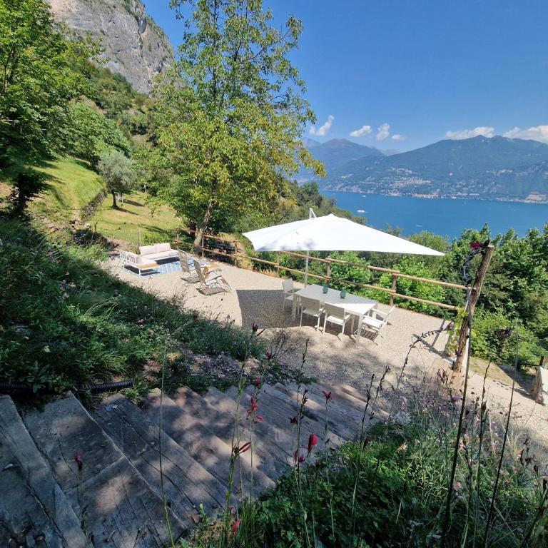 a patio with a white umbrella and a lake at Chalet Como Lake - Nature Retreat, foot access only in Griante Cadenabbia