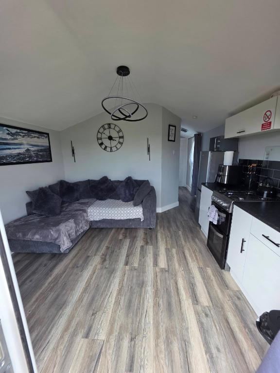 a living room with a couch and a clock on the wall at Lownie lodge in Leysdown-on-Sea