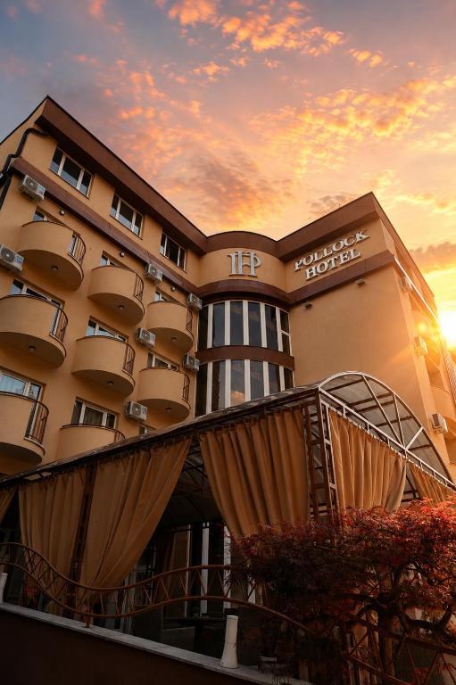 a hotel building with a sunset in the background at Pollock Hotel, Ribarska Banja in Ribarska Banja