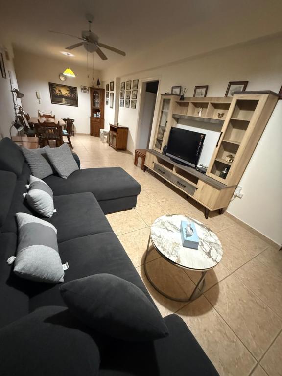 a living room with blue couches and a tv at Lux Family Suite & Pool in Larnaca