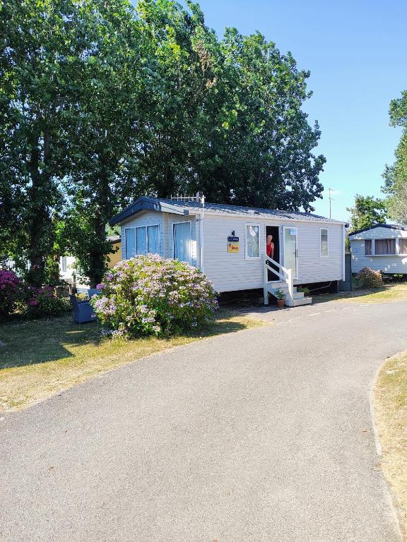a small white trailer with a person standing in the door at Rosie Caravan Selsey in Selsey