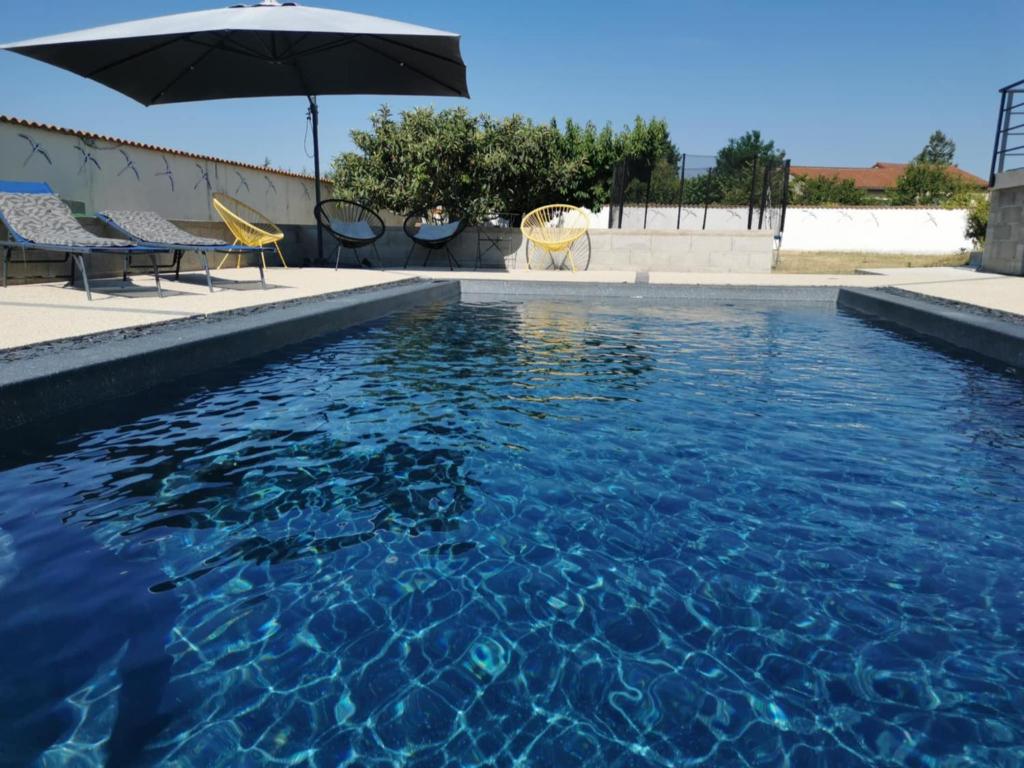 a swimming pool with an umbrella and chairs and a table at La Cigaline in Anneyron