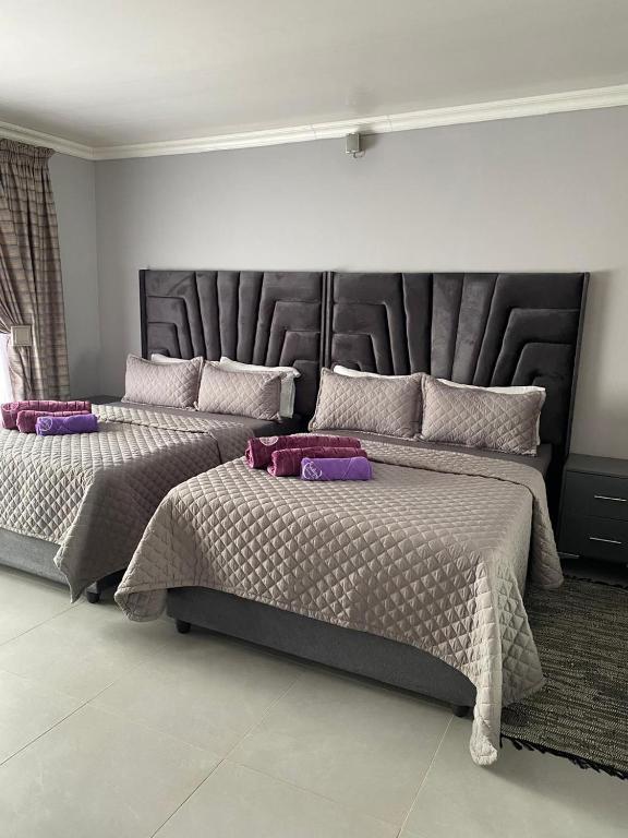 two beds in a bedroom with purple pillows on them at Florence contractors accomodation in Standerton