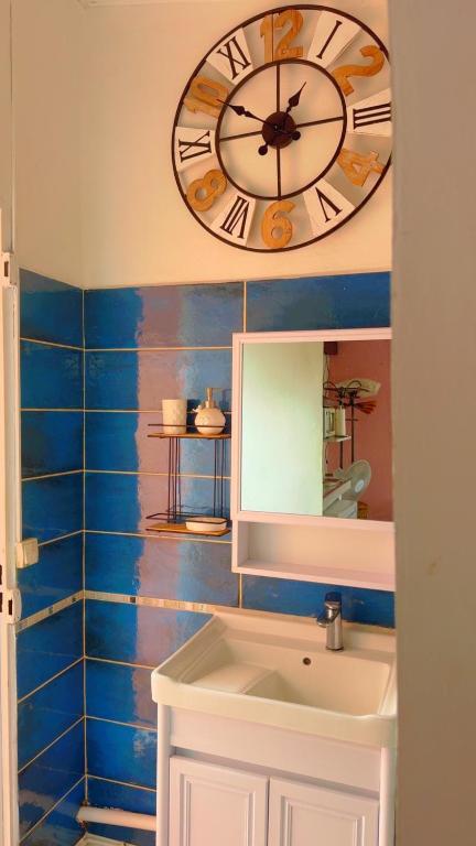 a clock on the wall above a sink in a bathroom at Kay Lili in Rivière-Pilote