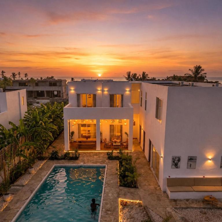 a house with a swimming pool in front of a sunset at Verdana House in Kiwengwa