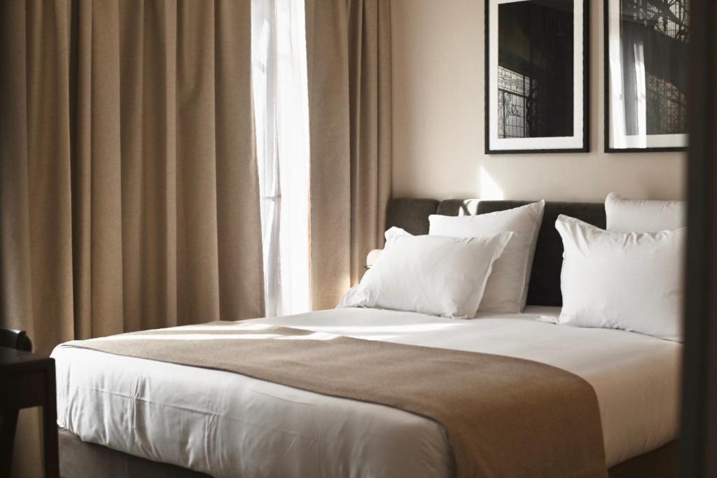a bedroom with a bed with white pillows and a window at Hotel Local 101 Beaurepaire in Paris