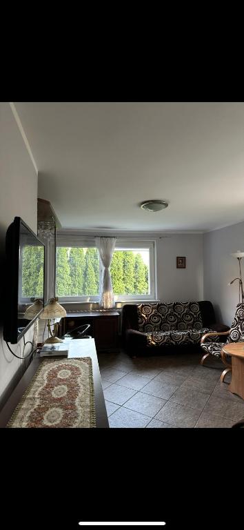 a living room with a couch and a large window at Przytulna Kawalerka Łeba in Łeba