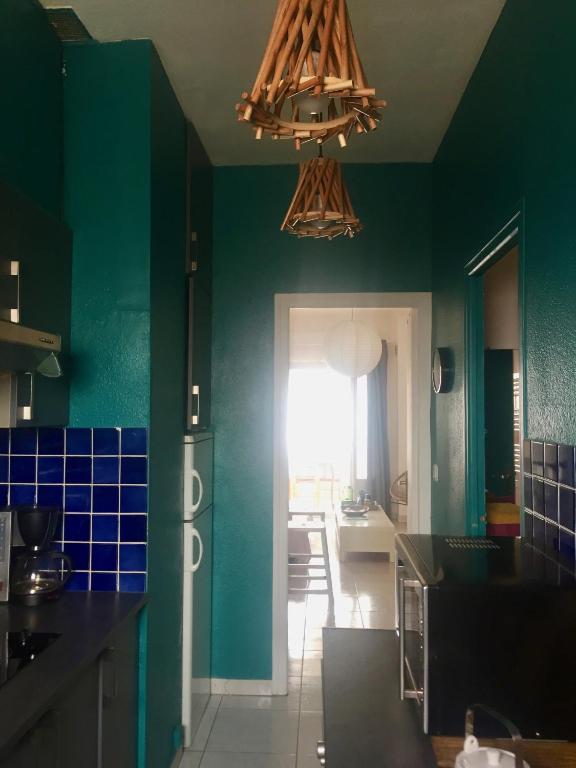 a kitchen with green walls and a chandelier at Appartement Canet in Canet-en-Roussillon
