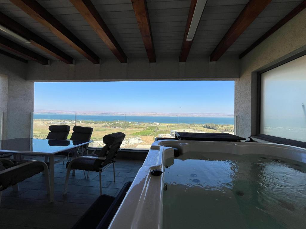 a room with a bath tub with a table and chairs at סוויטת נוף התכלת in Migdal