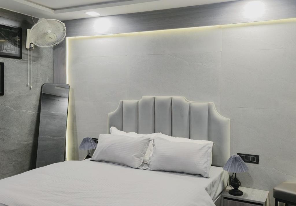 a bedroom with a white bed with white pillows at Grey Courtyard Entire Studio Taj Mahal Parking 3KM in Agra