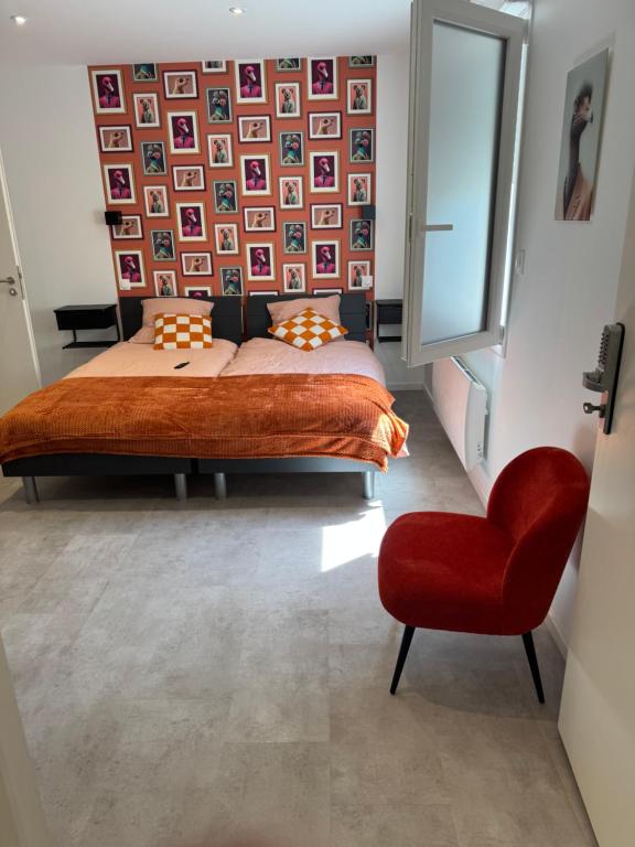 a bedroom with a bed and a red chair at Appart orange 25 m2 neuf RDC in Sainte-Marie-aux-Chênes