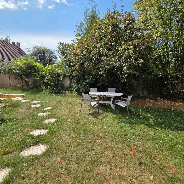 a picnic table and two chairs in a yard at Le Jardin de Courcelle in Gif-sur-Yvette