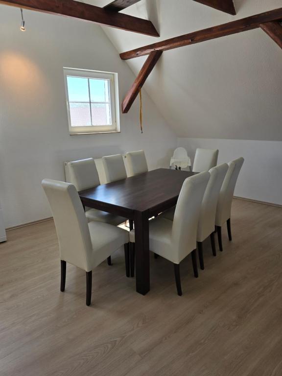 a dining room with a wooden table and white chairs at Ferienhaus An der Teufelsklippe in Veckenstedt