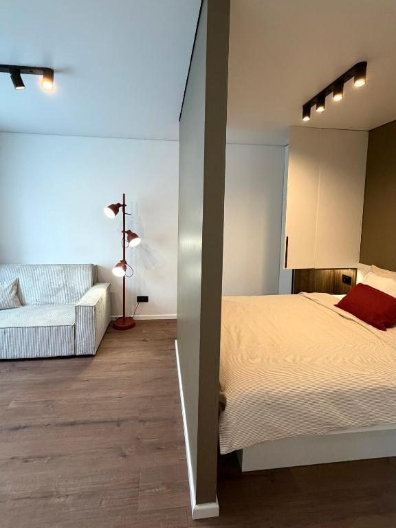 a bedroom with a white bed and a white couch at AC Central Station apartments in Daugavpils