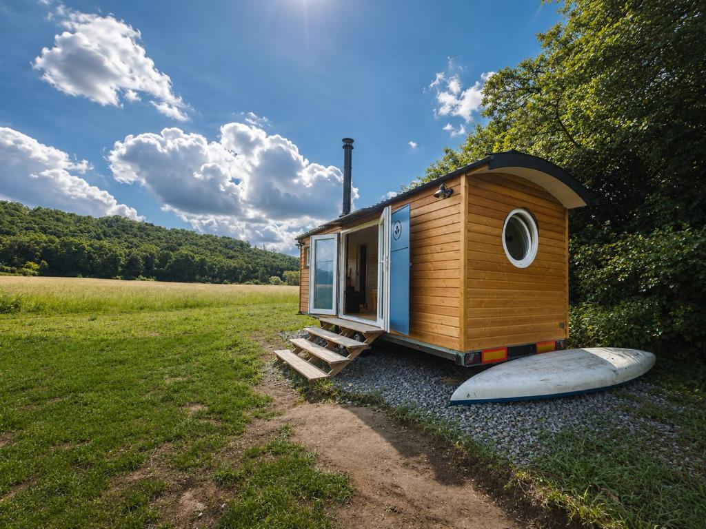a tiny house with a surfboard next to it at maringotka Hedvika glamping in Pašice