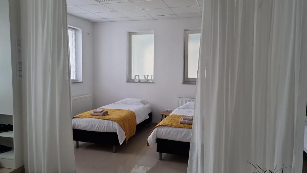 two beds in a room with white walls and a mirror at Lägenhet/Studio Grand in Jajce