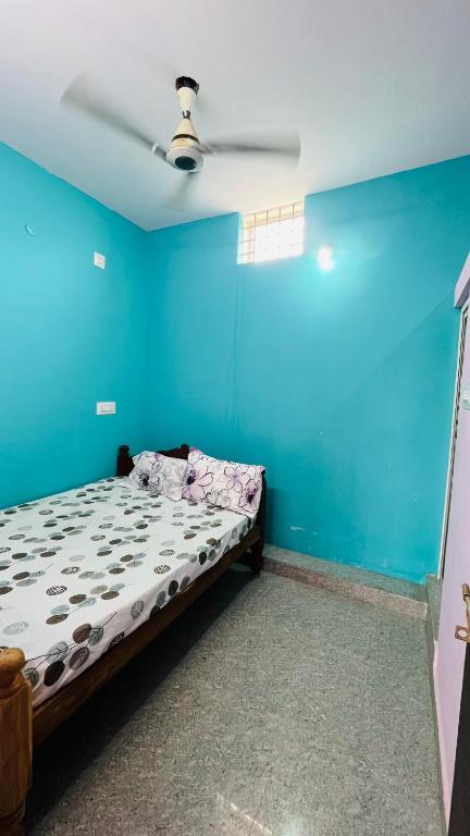 a bedroom with a bed with a blue wall at Radha krishna in Vellore