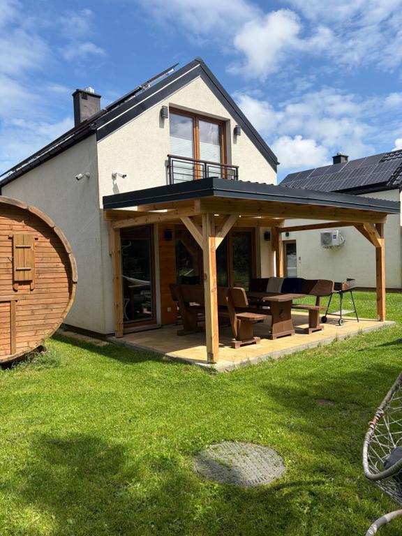 a house with a large deck with a patio at Zagroda ciszy in Lubiatowo