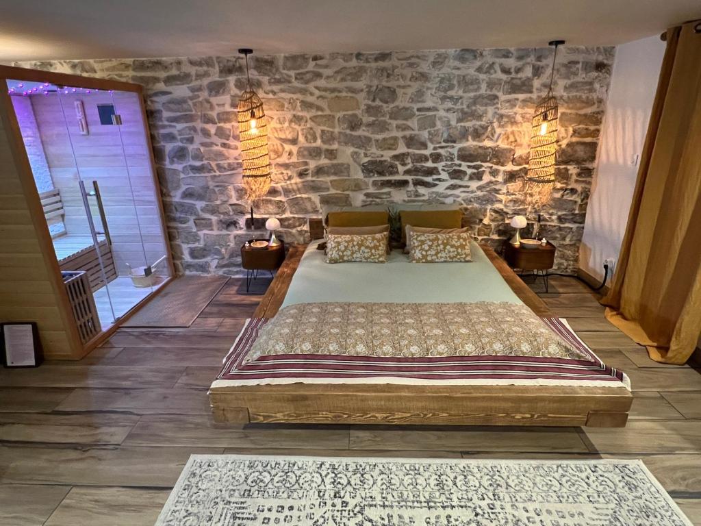 a large bed in a room with a stone wall at La parenthèse in Millau