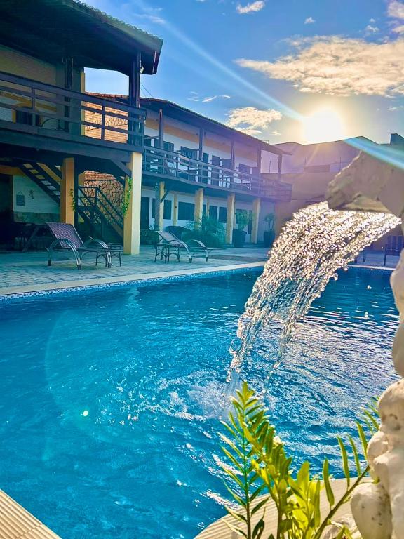 a pool with a fountain in front of a building at Pousada Estrela da Luz Refúgio in Muriú