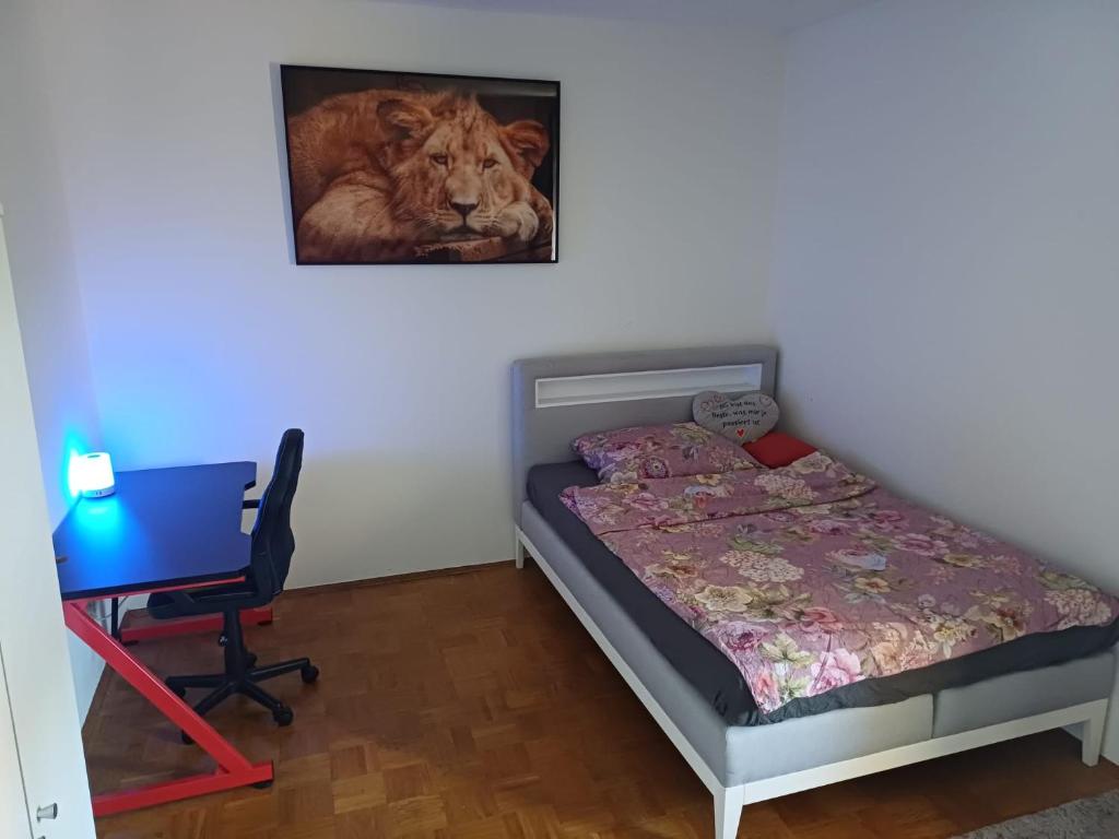 a bedroom with a bed and a desk and a painting of a lion at M&L Hartberg in Hartberg
