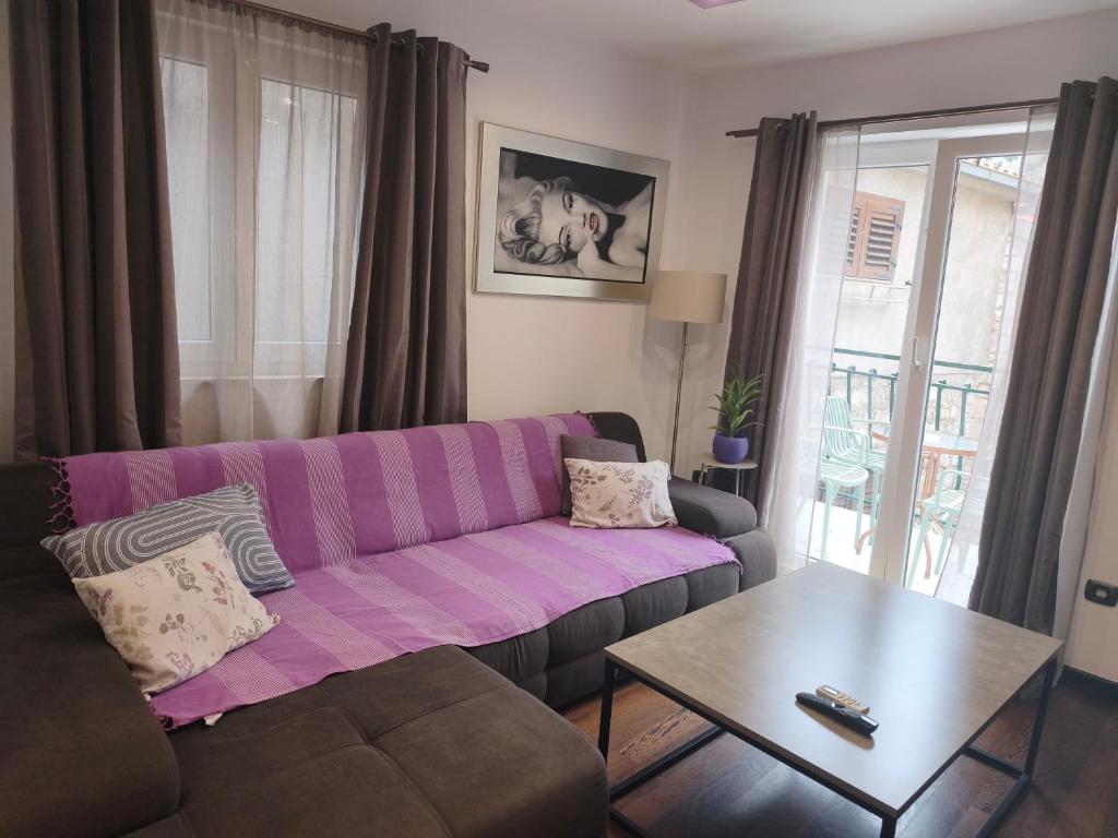 a living room with a purple couch and a table at Apartman Brzović in Omiš
