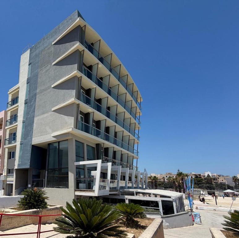 a building on the beach with palm trees in front of it at Water's Edge Hotel in Birżebbuġa