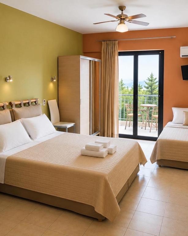 a hotel room with two beds and a balcony at Hotel Olivia in Agiokampos