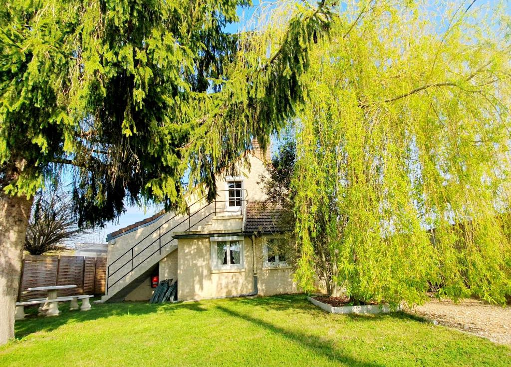 a house with a bench in front of a tree at Gite de Puisaye in Breteau