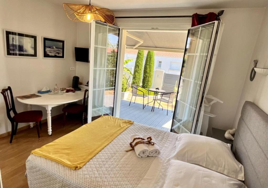 a bedroom with a bed and a table and a dining room at Chambres d'hôtes La Rose Des Sables in Les Herbiers