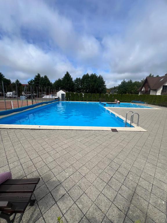 a large blue swimming pool with a bench next to it at Apartament Łeba in Żarnowska
