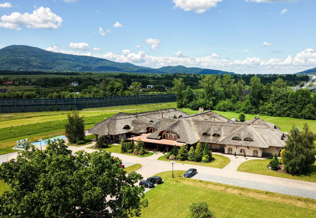an aerial view of a large house with mountains in the background at Dworek Góralski Restauracja Hotel & SPA in Łodygowice