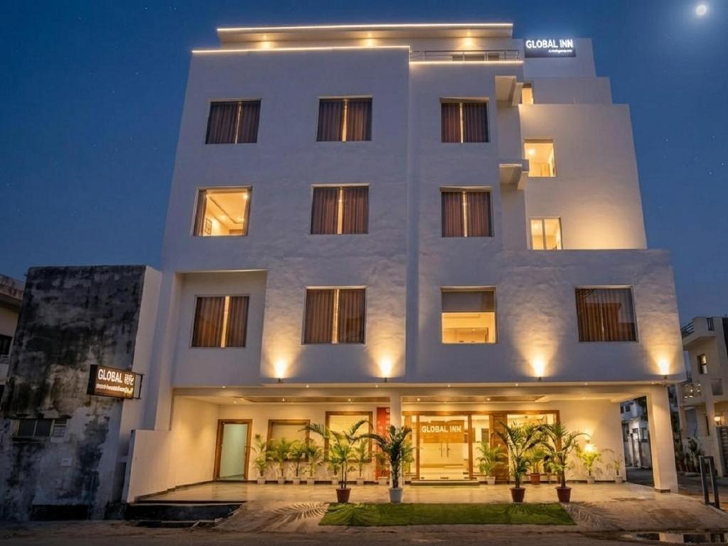 a white building with palm trees in front of it at Hotel Global Inn Gold in Lucknow
