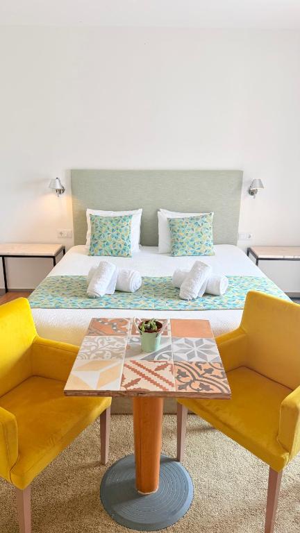 a bedroom with a bed with a table and yellow chairs at O Tourinho Ferrel in Ferrel