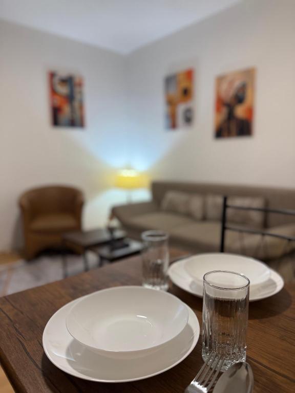 a wooden table with two plates and glasses on it at gvero apartments in Prilep