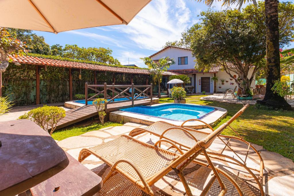 a backyard with a pool and chairs and an umbrella at Pousada das Orquídeas in Pirenópolis