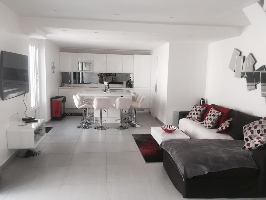 a living room with a couch and a kitchen at La maison spacieuse et confortable in Deauville