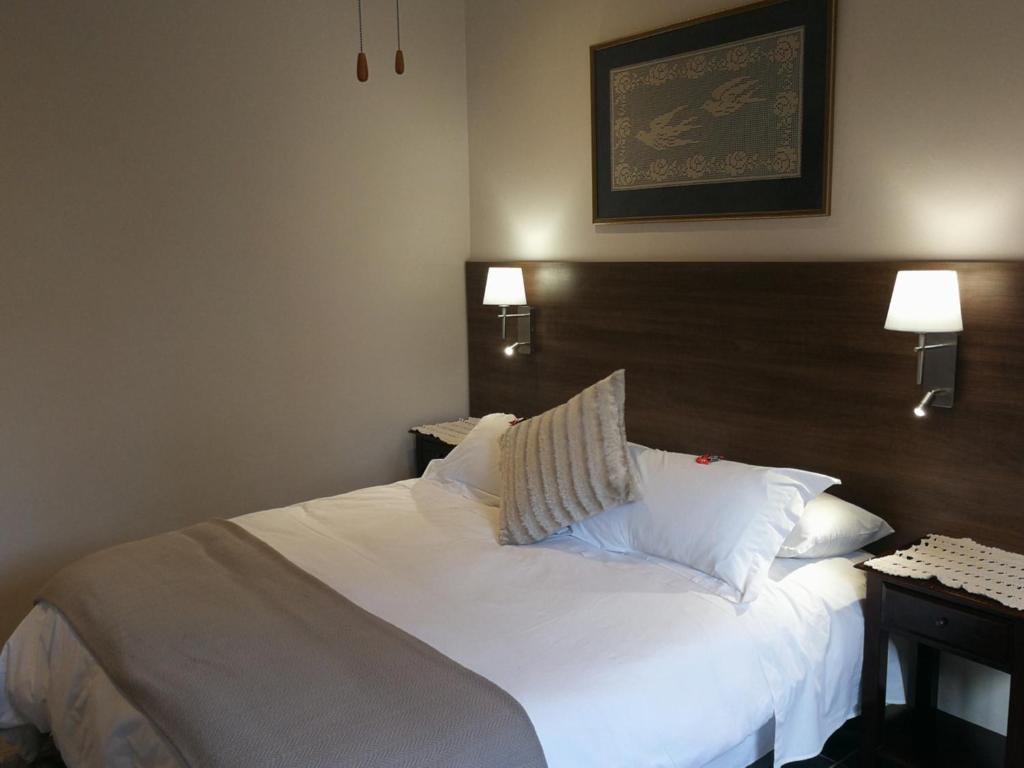 a bedroom with a bed with white sheets and pillows at Martin Villa in Somerset West