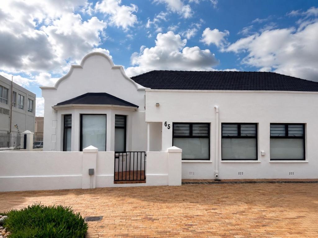 a white house with a black roof at Oceanfront Escape Beach House in Strand