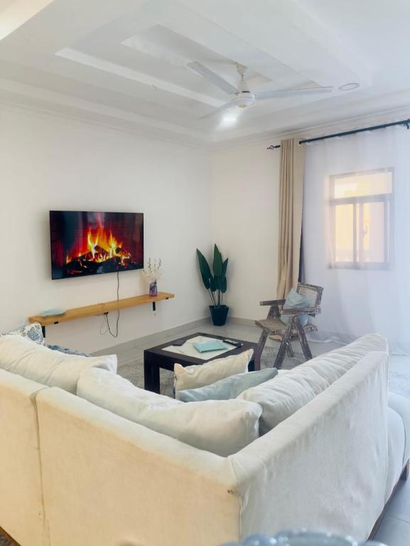 a living room with white couches and a fireplace at Imani staycation Penthouse Diani in Diani Beach