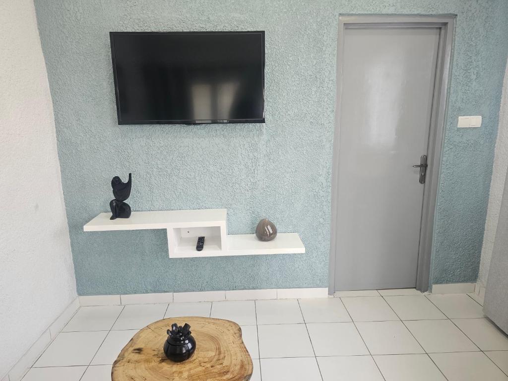 a room with a tv on a wall with a table at Domaine Béthania in Tadiénou