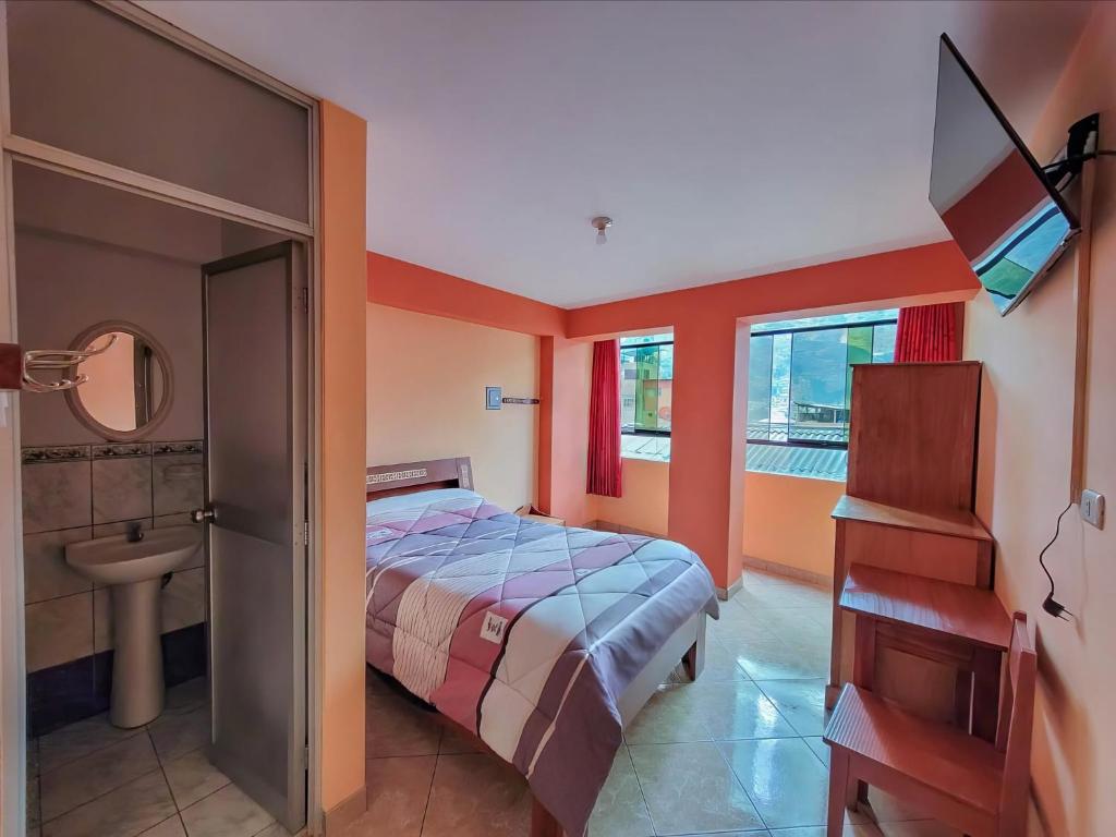a bedroom with a bed and a sink and a mirror at Hostal Huagancu in Huari