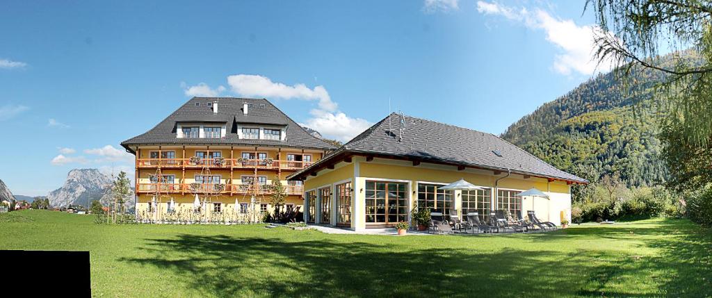 duży budynek na polu z górą w obiekcie Hotel Hochsteg Gütl | Traunsee Salzkammergut w mieście Ebensee