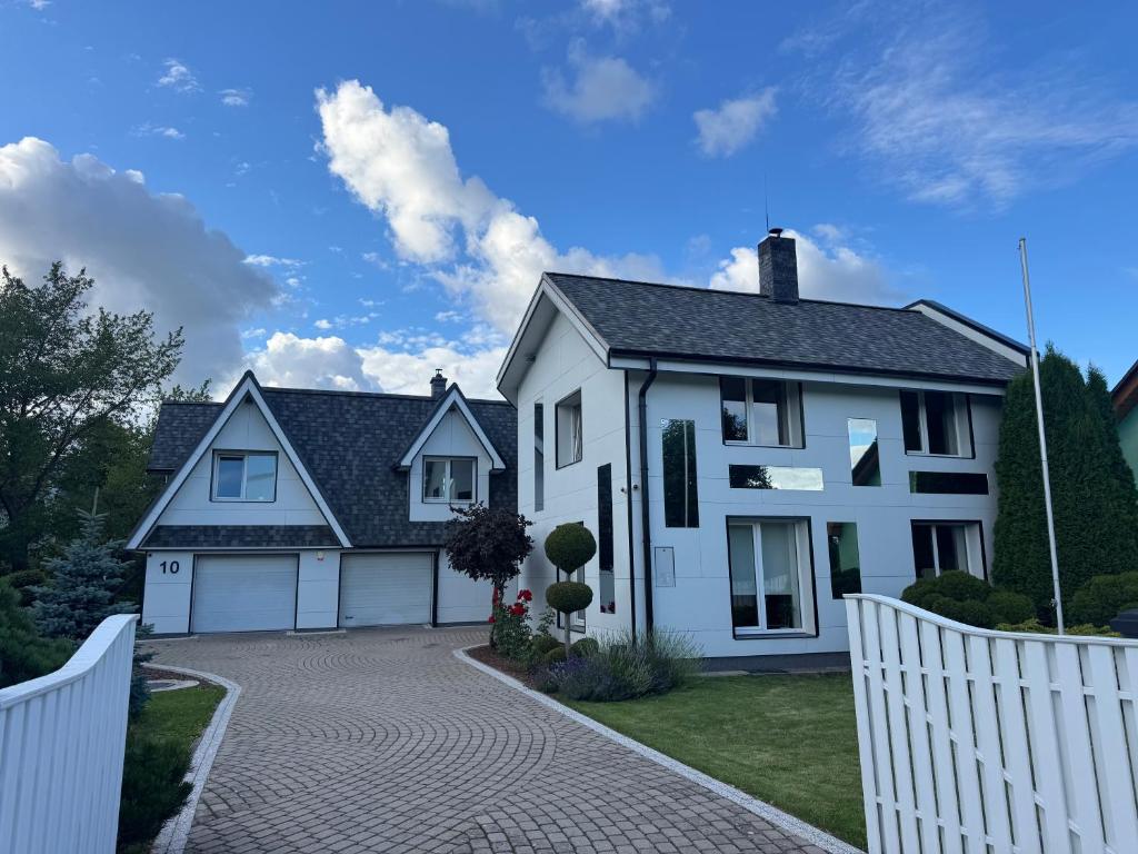 a white house with a white fence and a driveway at Kaleju 10 Apartment in Tukums