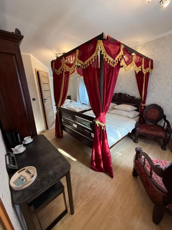 a bedroom with a canopy bed with red curtains at Tadż Mahal Apartament in Sulechów
