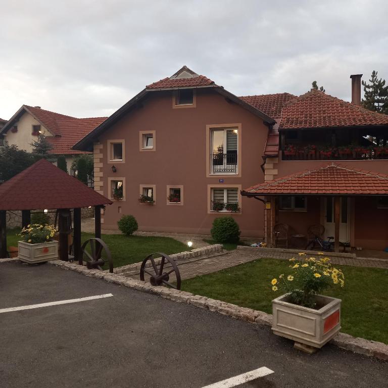 a house with a gazebo and flowers in a yard at Apartmani Aleksijević Zlatibor in Zlatibor