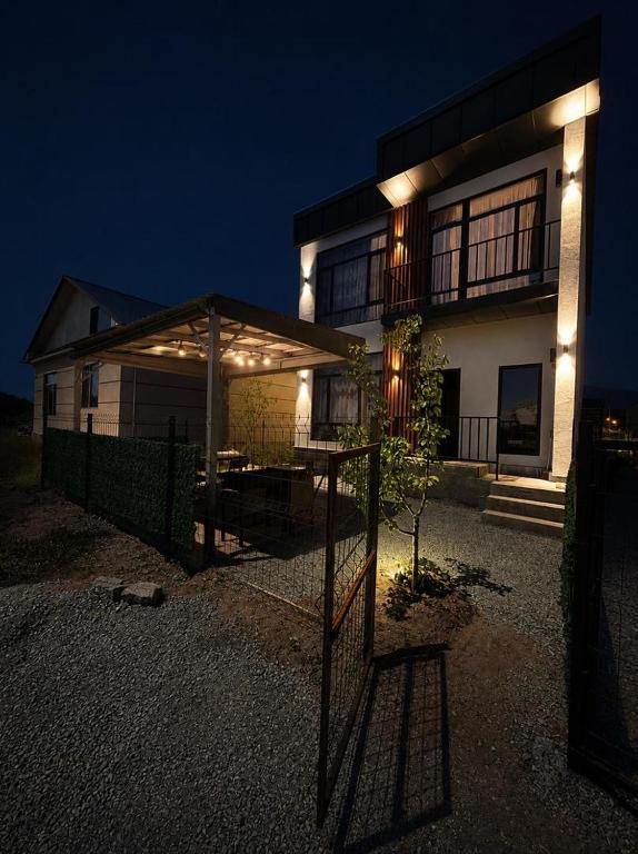 a house with a fence in front of it at night at Береке гостевой дом in Bosteri