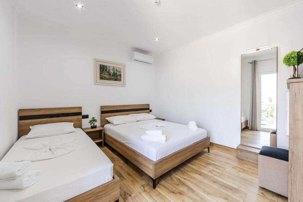 two beds in a room with white walls and wooden floors at Bliss by PikHost in Gjirokastër