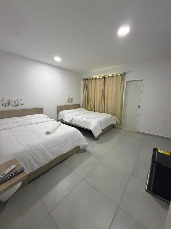 a bedroom with two beds and a television in it at Hotel Boutique Trinitarias in Valledupar
